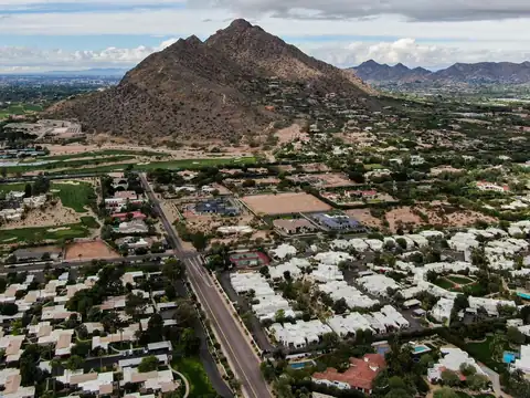 Homes with white flat roofs below a bare desert mountain in the Scottsdale area, seen from the air